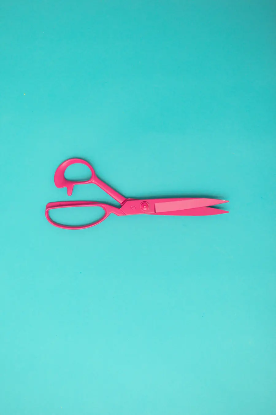Tijeras rosadas sobre fondo turquesa